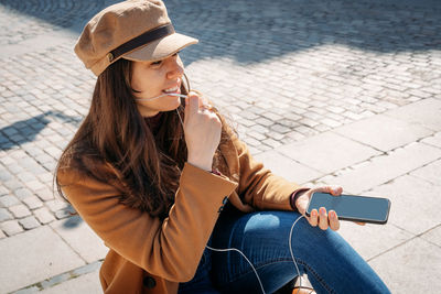 Young woman using mobile phone while sitting in camera