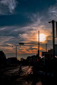 Silhouette city street against dramatic sky during sunset