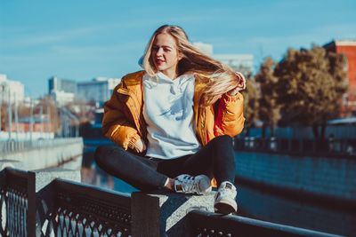 Midsection of woman sitting on railing