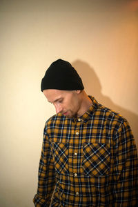 Man looking away while standing against wall