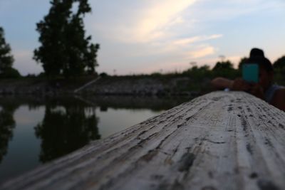Close-up of wood against lake during sunset
