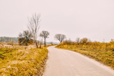 Road amidst field against clear sky