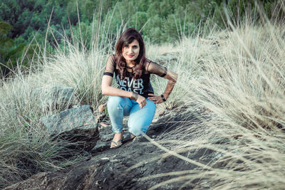 Portrait of smiling young woman sitting on land