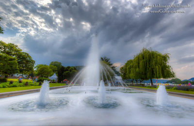 Fountain against cloudy sky