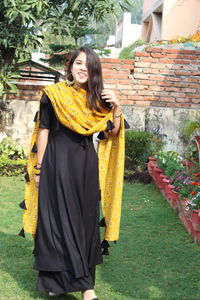 Young woman standing against yellow wall