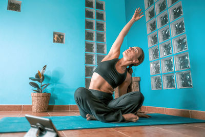 Full length of man with arms raised against wall