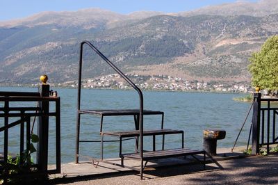 Chairs by sea against mountains