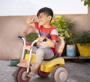 Full length of boy sitting in tricycle outdoors