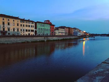 Buildings by river against sky in city