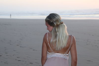 Woman standing at beach against sky