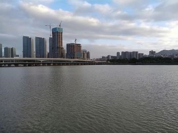 Sea by buildings against sky in city