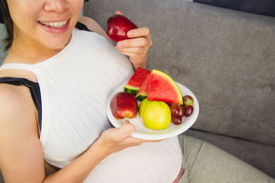 Midsection of woman holding apple