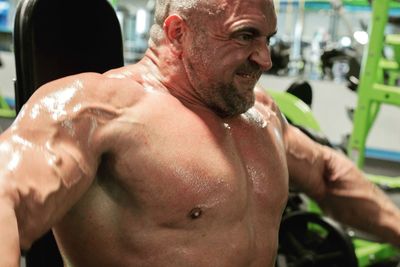 Close-up of shirtless muscular man exercising in gym