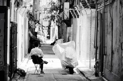 Man sitting on sidewalk in city