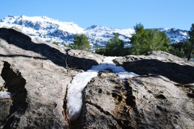 Close-up of snow on rock against sky