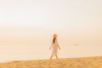 Woman standing at beach against sky