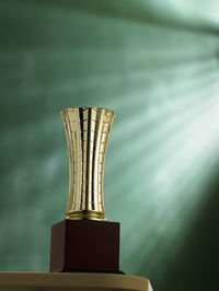 Close-up of trophy on table against green wall