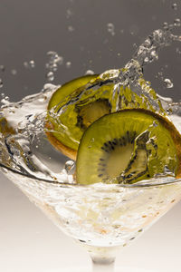 2 kiwi slices falling into drink