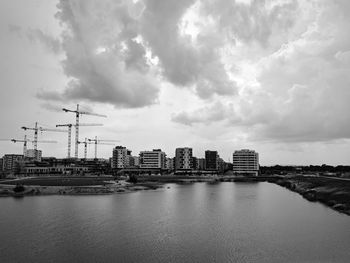 Buildings by river against sky in city