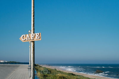 Road sign against clear blue sky