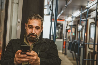 Man reading from mobile phone screen while traveling on metro. wireless internet on public transport