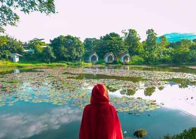 Rear view of woman standing by lake against sky