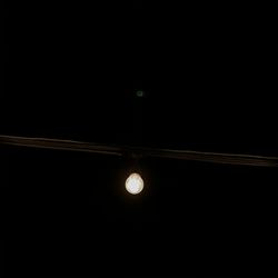 Low angle view of illuminated light bulb against dark sky