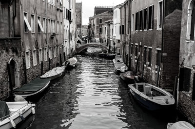 Boats moored in canal amidst buildings in city