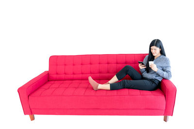 Woman sitting on sofa against white background