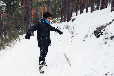 Full length of boy playing with snow in forest