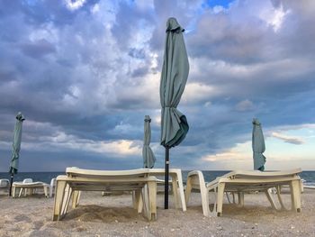 Empty chairs on beach against sky