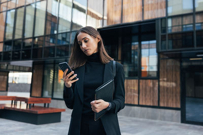 Portrait of young woman standing in city