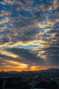 View of city against cloudy sky during sunset