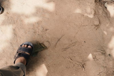 Low section of man standing on sand