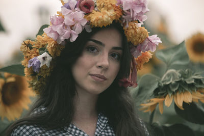 Portrait of young woman wearing flowers while standing outdoors
