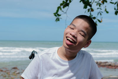 Close-up of smiling boy sitting on wheelchair against sea