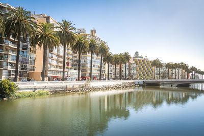 Buildings by river against clear sky