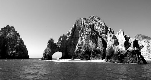 Calm sea with rocky headlands against clear sky