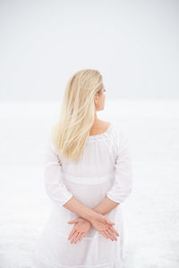 Beautiful young woman standing against white background