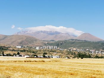 Scenic view of field and mountains against blue sky