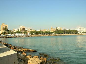 Scenic view of river by city against clear sky