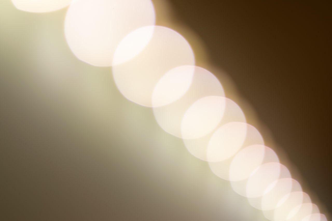 DEFOCUSED IMAGE OF ILLUMINATED LIGHTS AGAINST SKY