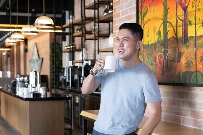 Handsome guy smiling while having a cup of coffee in the morning