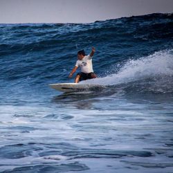 Man surfing in sea against sky