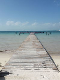 Surface level of wooden pier at beach against sky