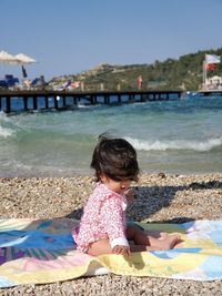 Rear view of baby girl sitting on beach