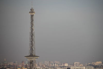 Communications tower in city against clear sky