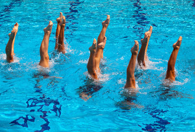 Low section of young women with feet up in swimming in pool