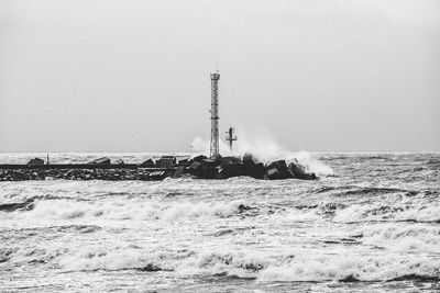 Lighthouse by sea against clear sky