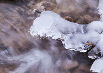 Photography with contrasts of frozen and running water, spring water flows over pieces of limestone